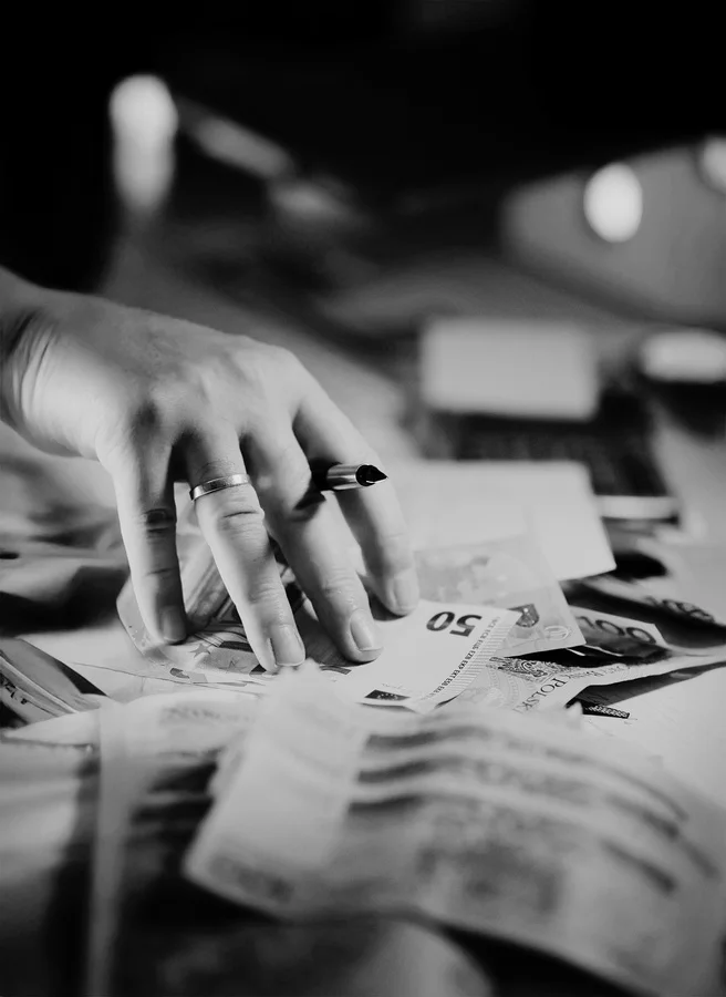 Hands counting bank notes spread across a desk
